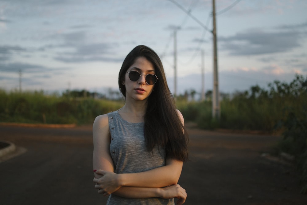 a woman wearing sunglasses standing in the middle of a road