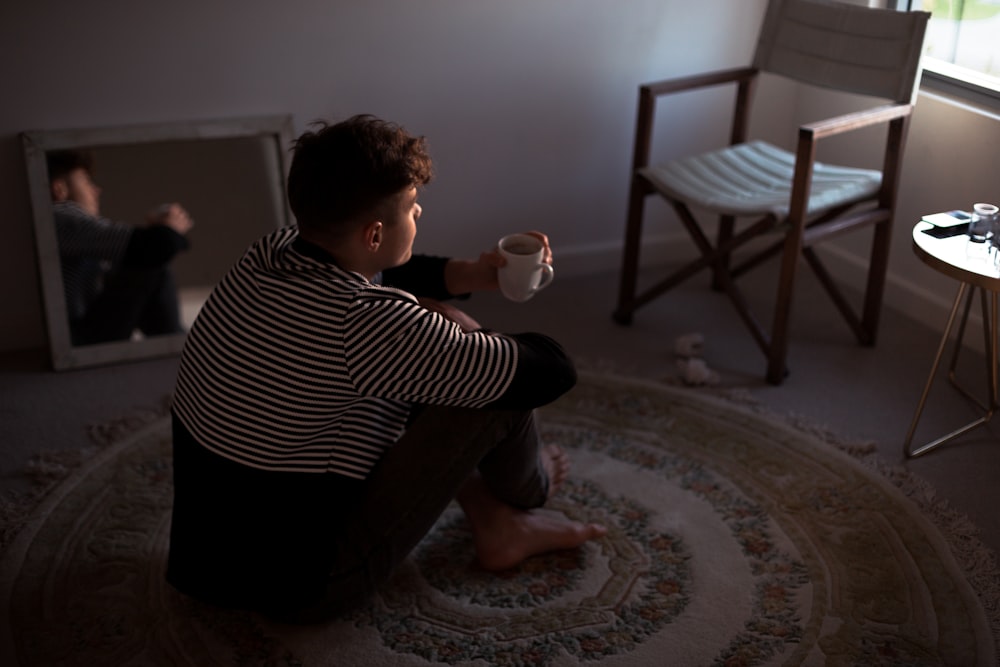 man sitting on rug in front of window