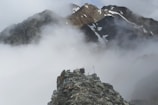 A hiker standing on a rocky ridge overlooking misty Macedonian mountains at dawn.