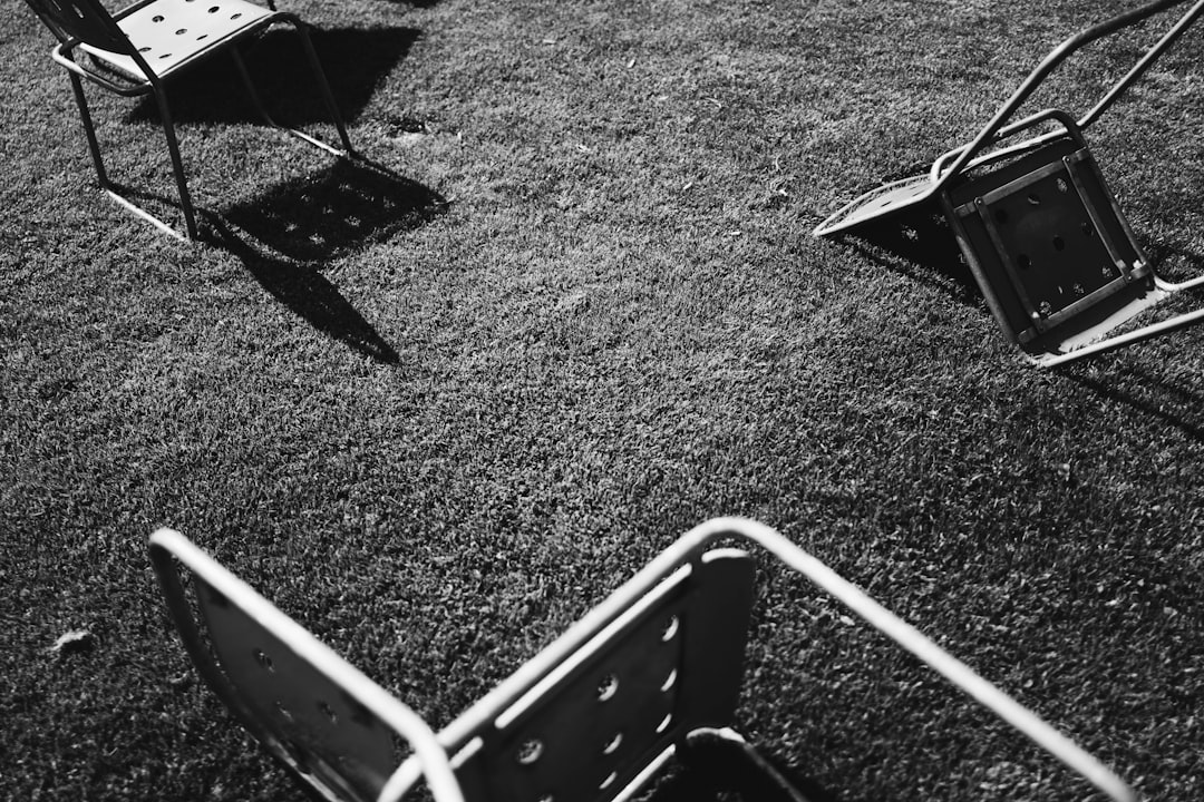 grayscale photo of gray chairs on grass field