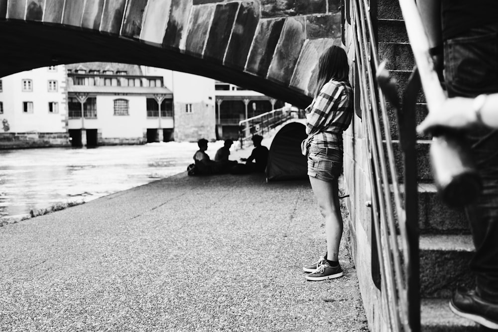 Mujer de la fotografía en escala de grises apoyada en las escaleras de hormigón al aire libre