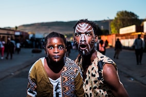 two people with face paints taking photo in street