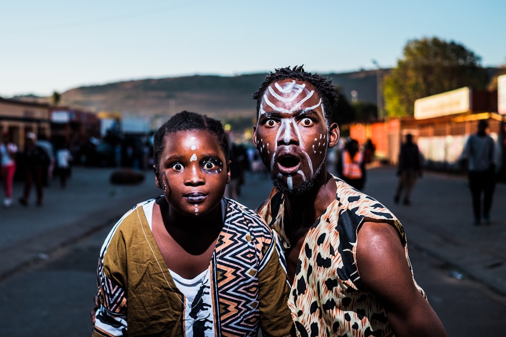 two people with face paints taking photo in street