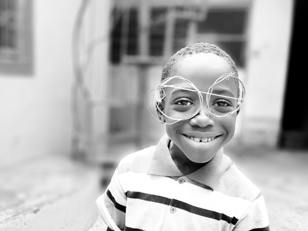 grayscale photography of boy standing on ground front of house