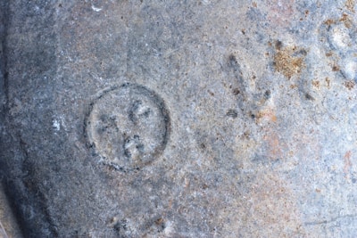 A close-up of an ancient, weathered symbol carved into stone, glowing softly in natural light.