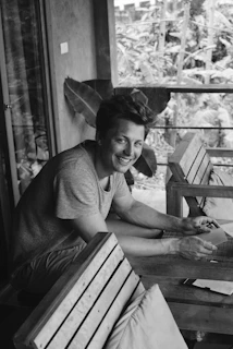 The model laughing candidly while seated on a rustic wooden bench.