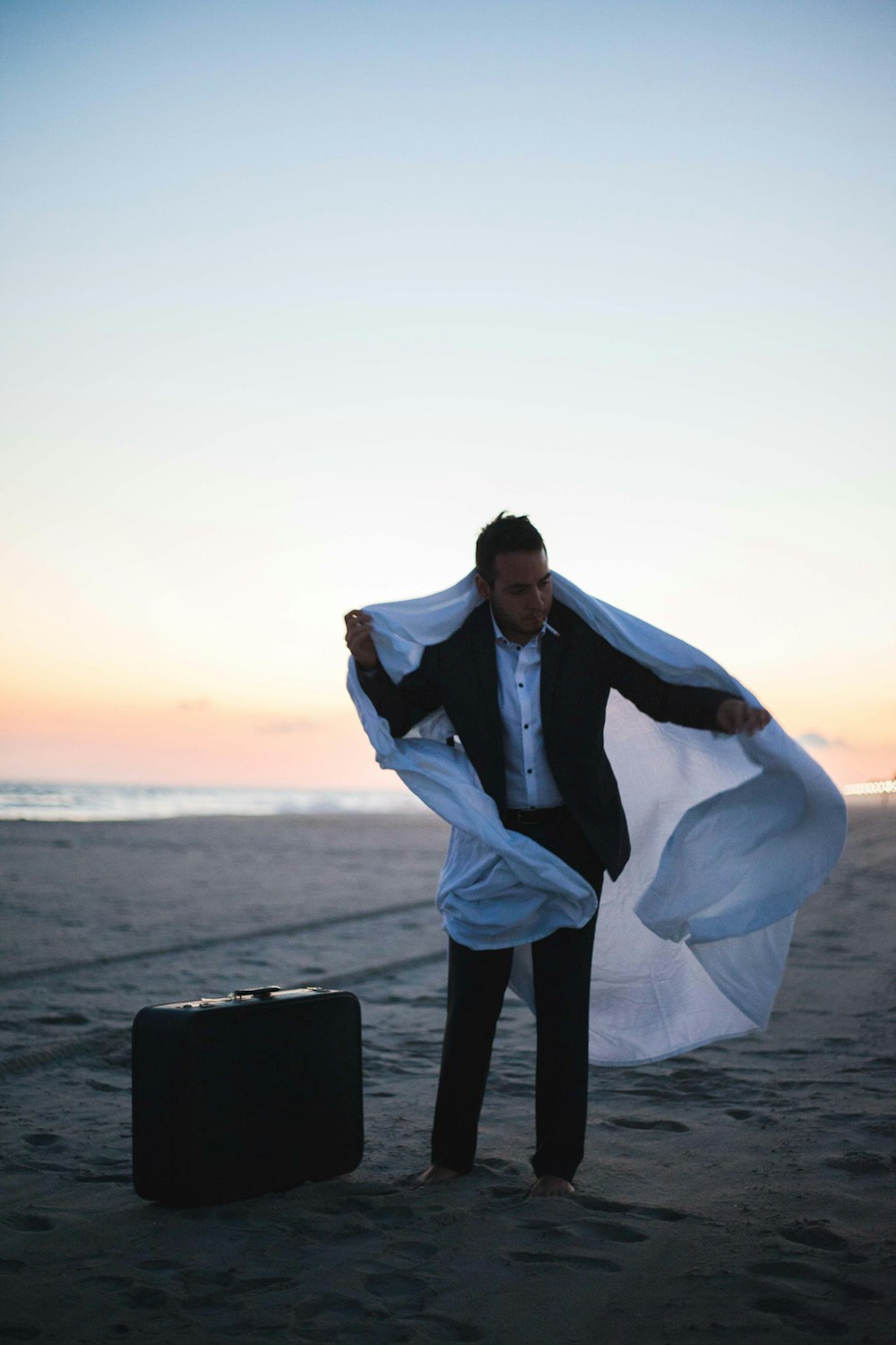 man in black suit holding white textile