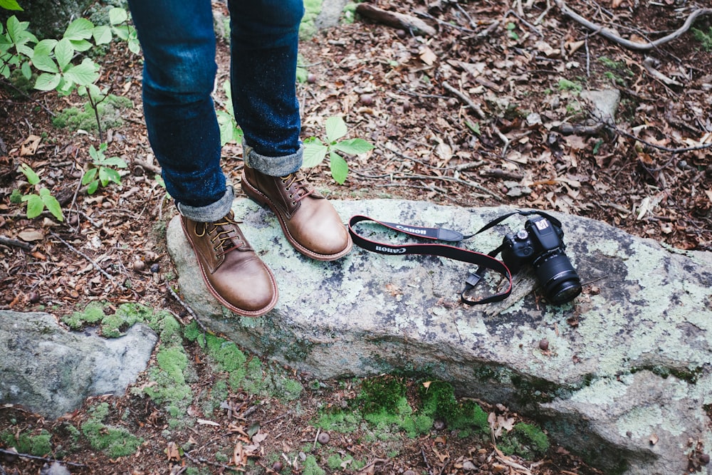 person in blue denim jeans and brown leather shoes standing on brown soil