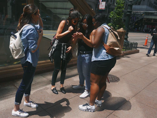A group of girls aged 8-19 laughing and walking together on a sunlit city street, showcasing camaraderie.