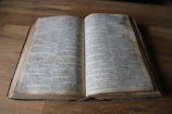 Close-up of a worn book cover with elegant serif typography on a wooden desk.