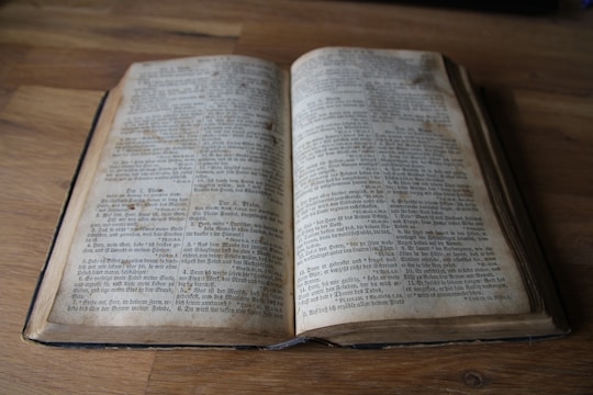 A restored antique book opened on a wooden table, showing repaired pages and a renewed spine.