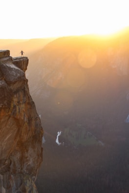 The main character standing on a cliff overlooking a vast fantasy landscape at sunset.