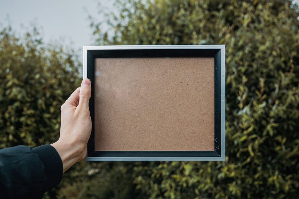 person holding rectangular white and black frame