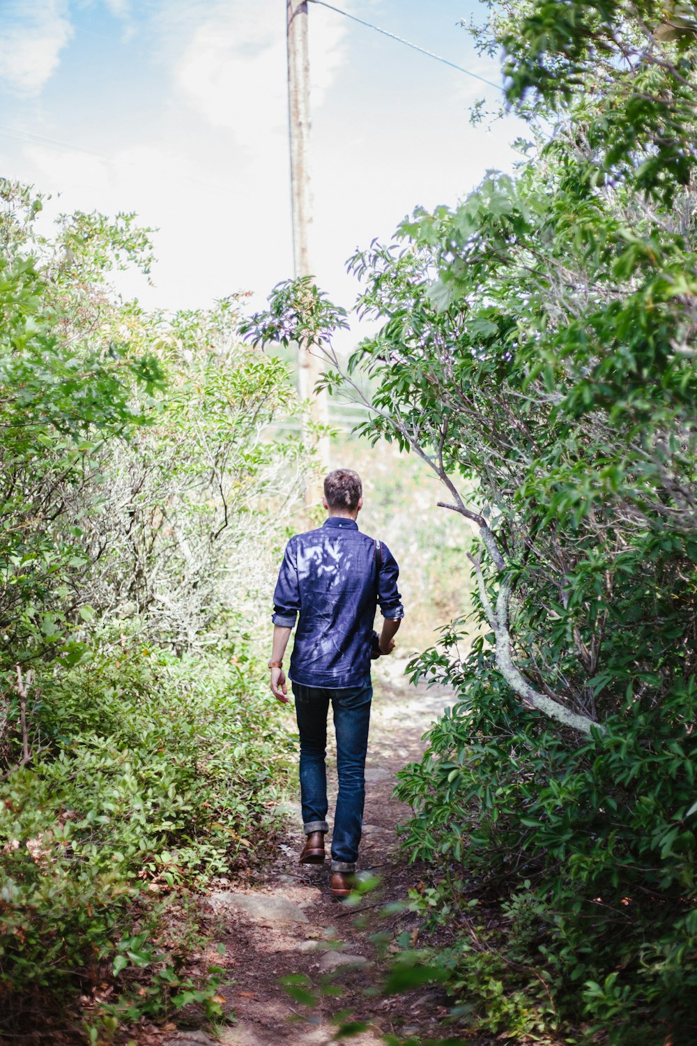 man in blue shirt and blue denim jeans standing on green grass during daytime