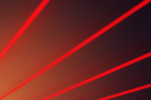 Multiple bright red diagonal lines stretch across a dark gradient background, creating a dynamic and futuristic effect.
