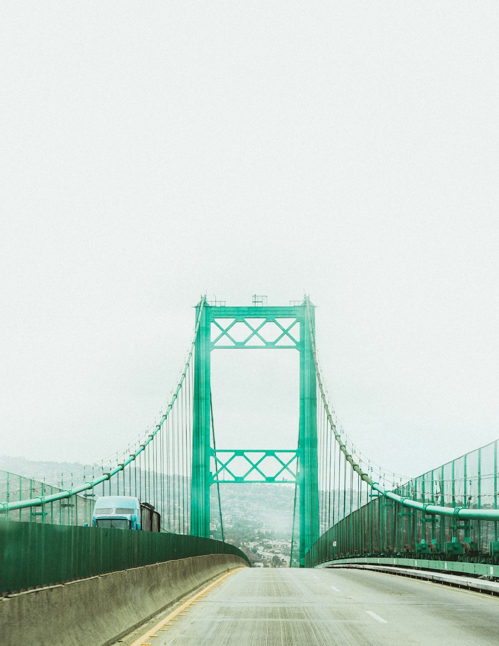 a truck driving across a bridge on a foggy day