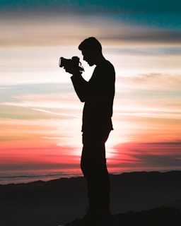 silhouette photo of man holding camera