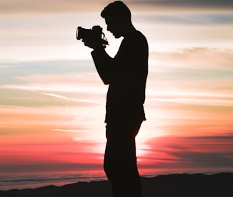 silhouette photo of man holding camera