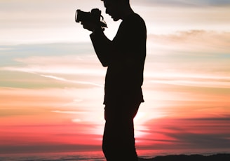 silhouette photo of man holding camera