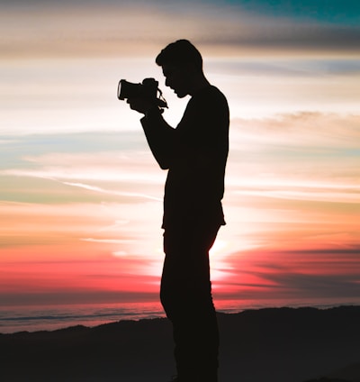 silhouette photo of man holding camera