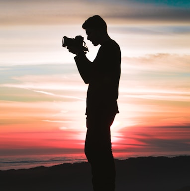 silhouette photo of man holding camera