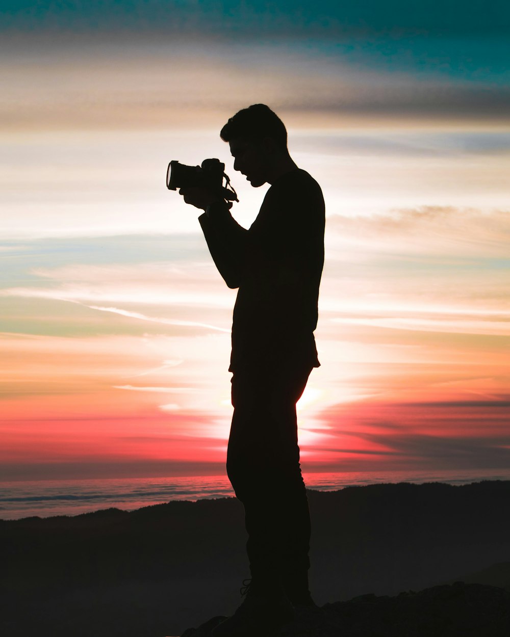 silhouette photo of man holding camera