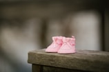 A collection of baby shoes and socks laid out on a wooden surface with gentle sunlight.