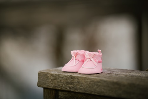 A close-up of soft baby shoes and accessories arranged neatly on a wooden surface