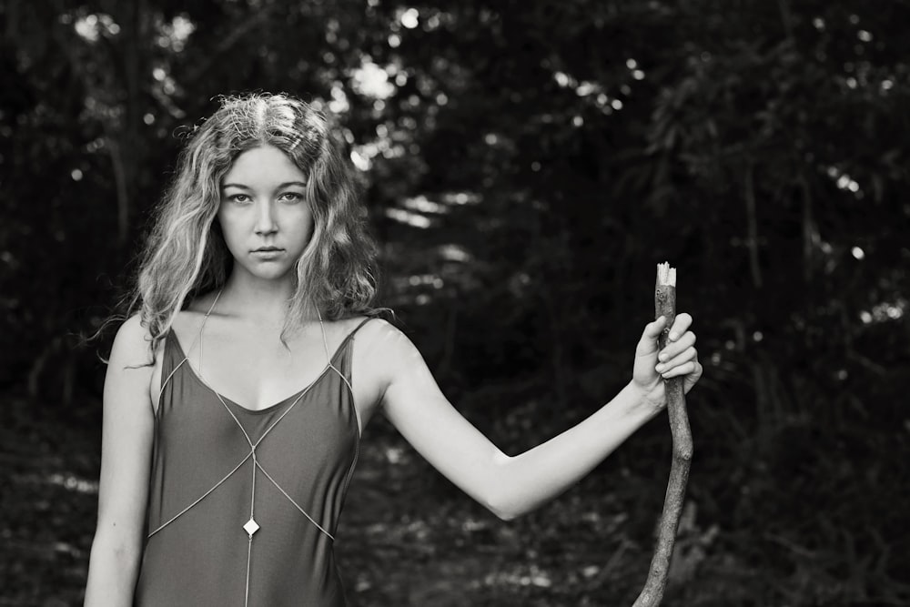 grayscale photo of woman standing while holding stem