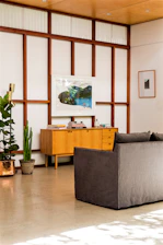 Artistic shot of a minimalist living room featuring custom modular furniture in dark wood tones with gold accents.