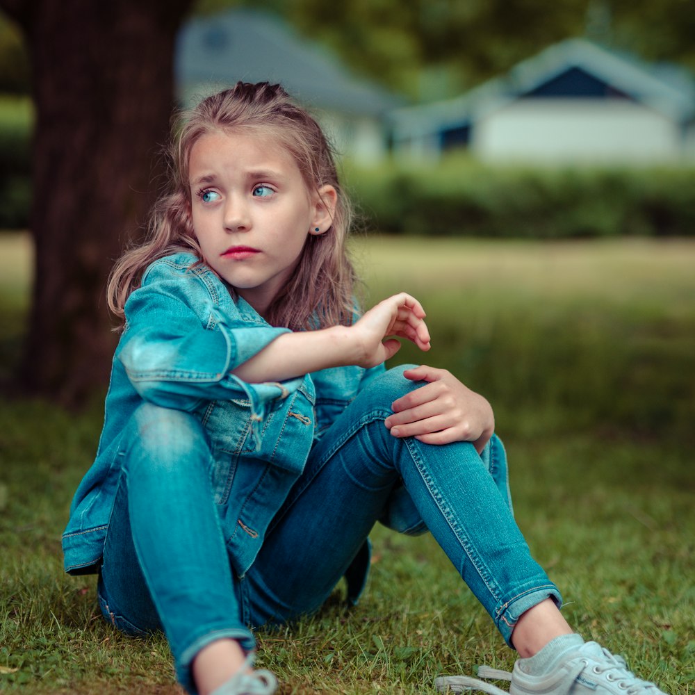 木の近くに座っている女の子の選択焦点写真