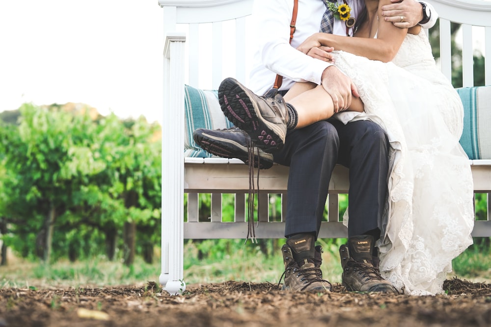 woman and man sitting on white wooden bench