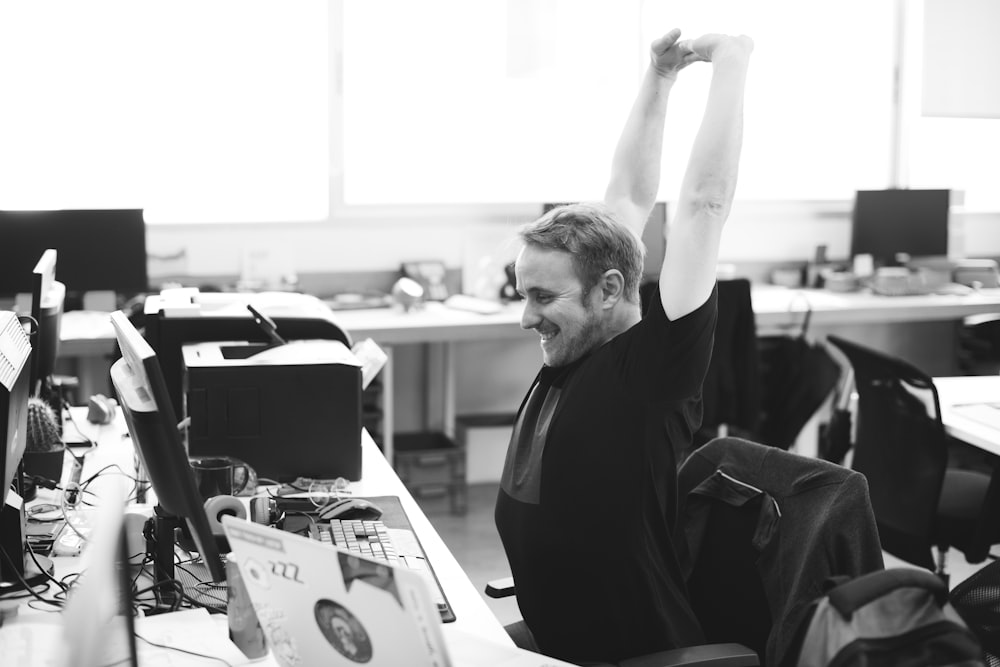 A man stretching his hands over his head while working in an office