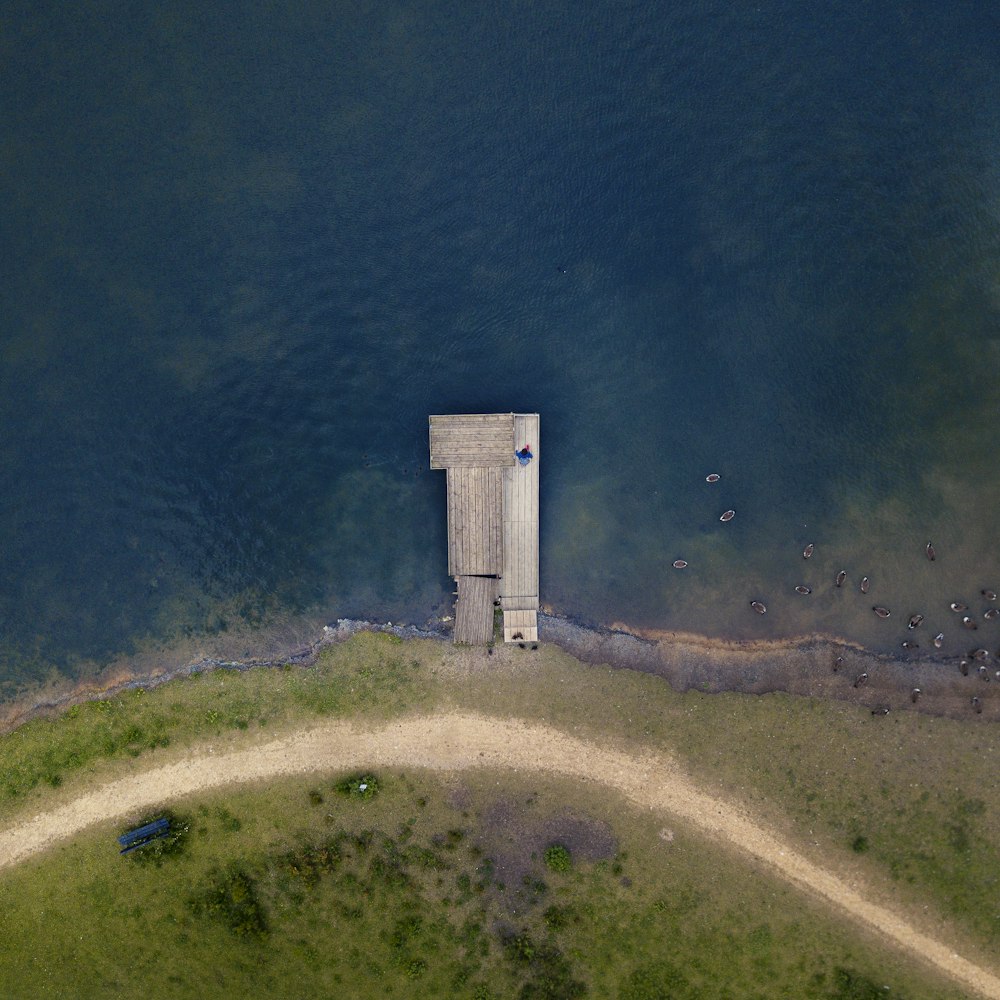 Luftaufnahme einer Person, die auf einem braunen Holzsteg in der Nähe eines ruhigen Gewässers steht