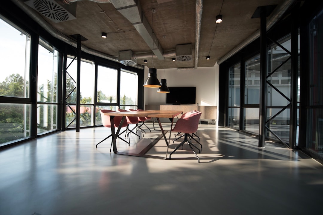 A spacious boardroom with a wooden table and pink chairs