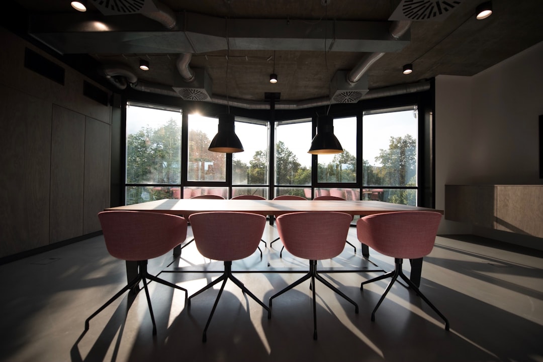 An unfurnished conference room with a table and eight pink chairs