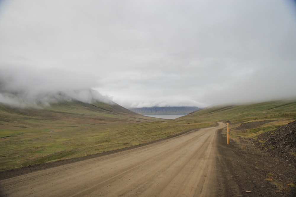 gray asphalt road near green grass field and mountain during daytime