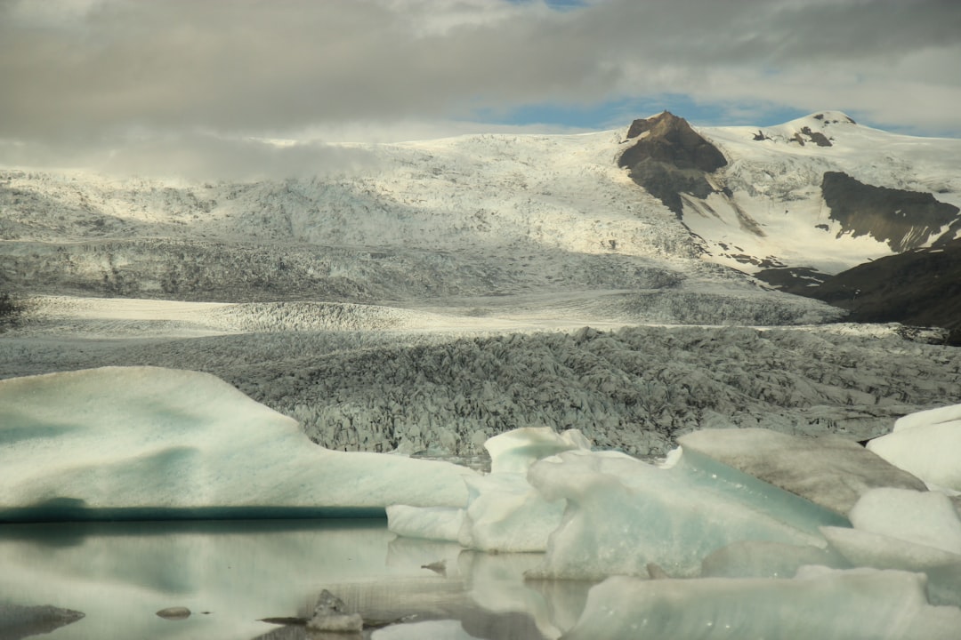 snow covered mountain near body of water during daytime