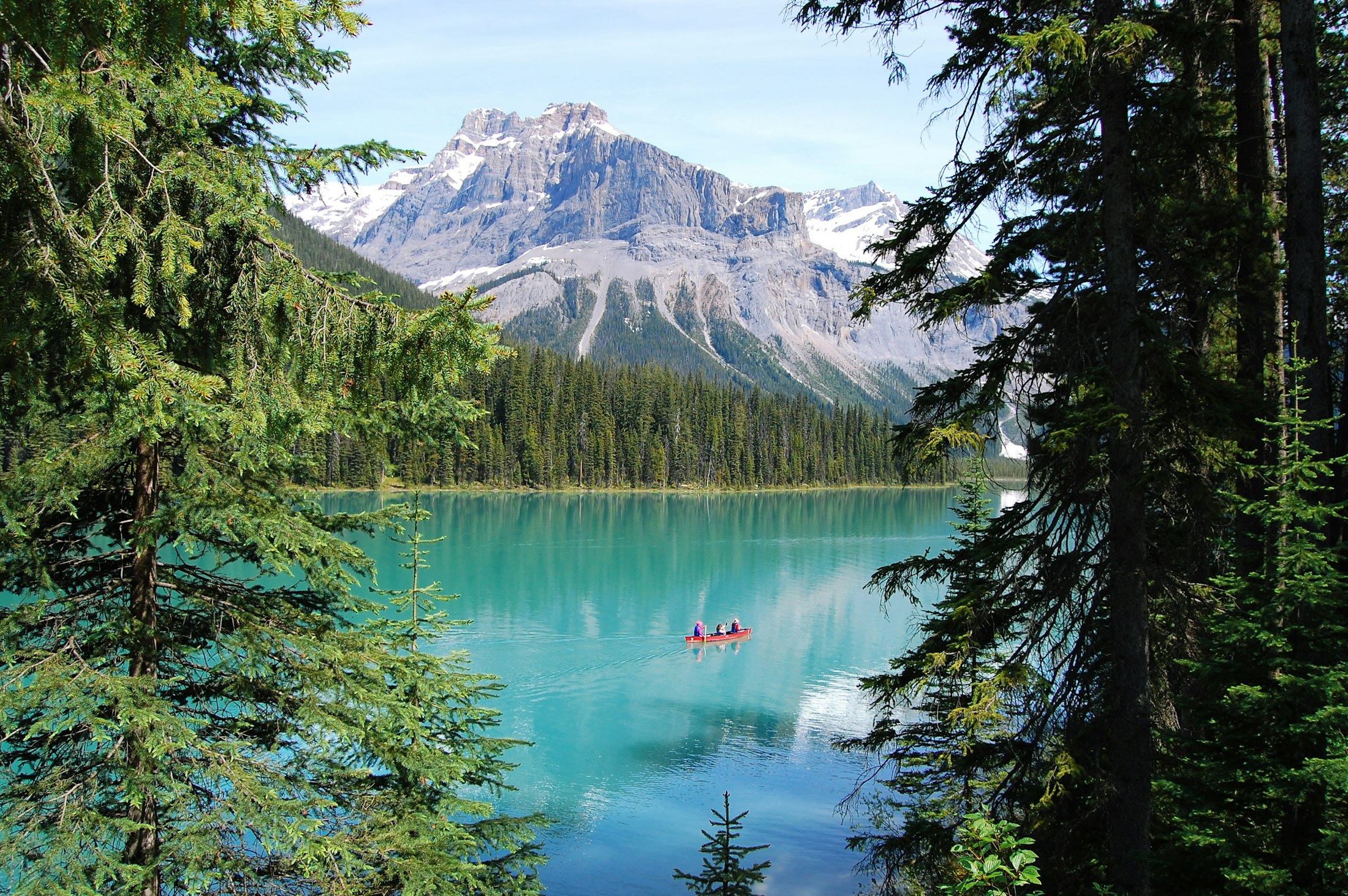 Canot rouge sur un lac turquoise bordé d'épinettes
