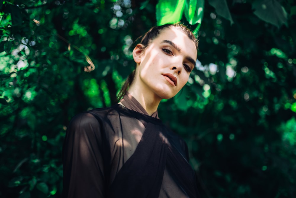 woman wearing sheer top under green leafed plant