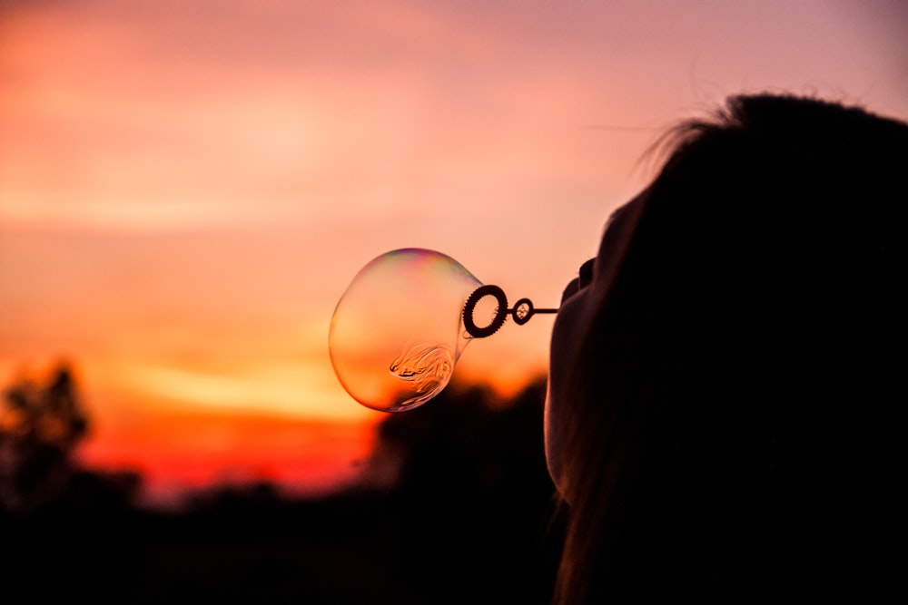 shallow focus photography of person blowing bubble balloon