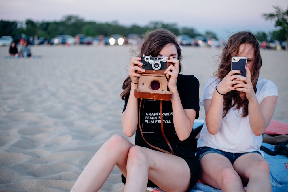 two woman taking photos using smartphone and camera