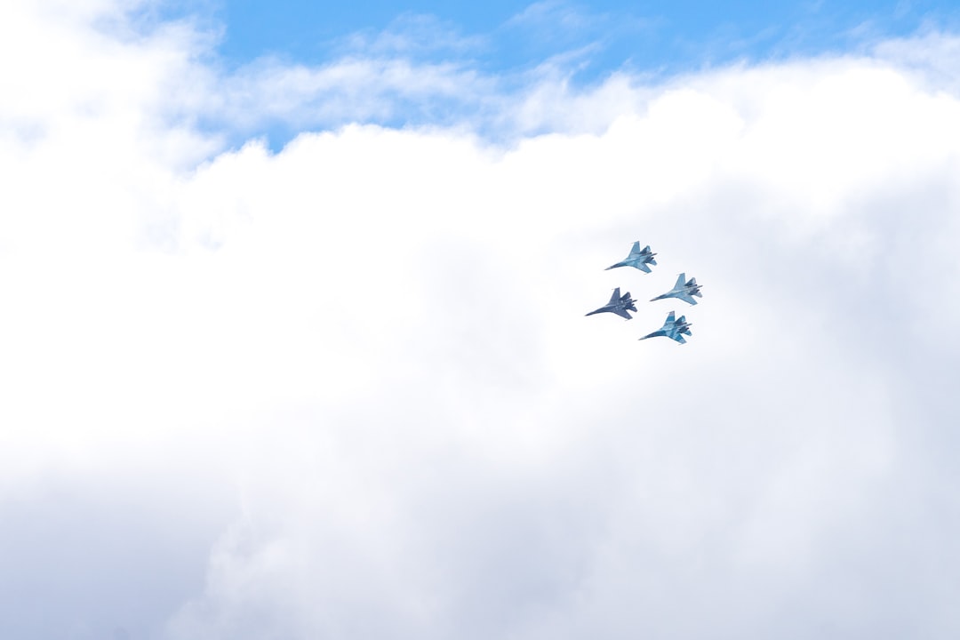 four blue fighting planes surrounded white clouds,