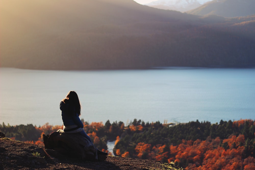 silhouette of person sitting on peak of mountain