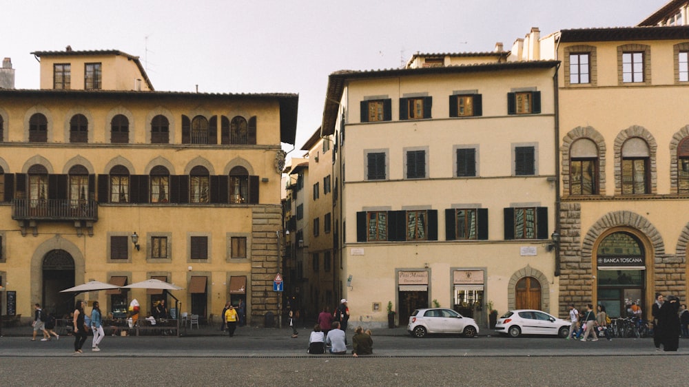 fotografia di persone che camminano tra la strada e l'edificio durante il giorno