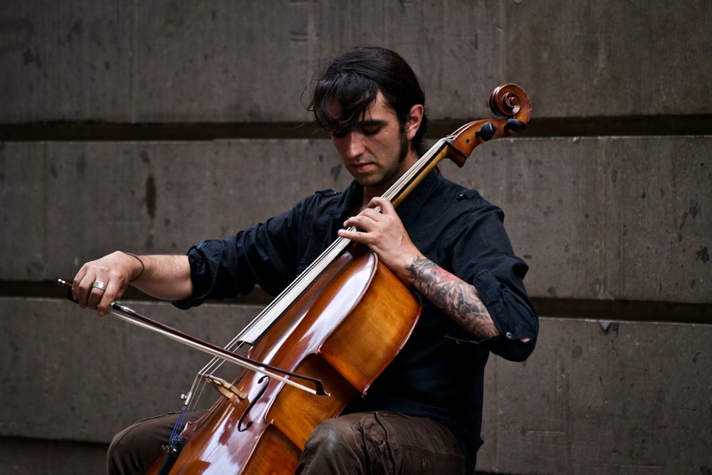 Hombre tocando el violonchelo cerca de la pared