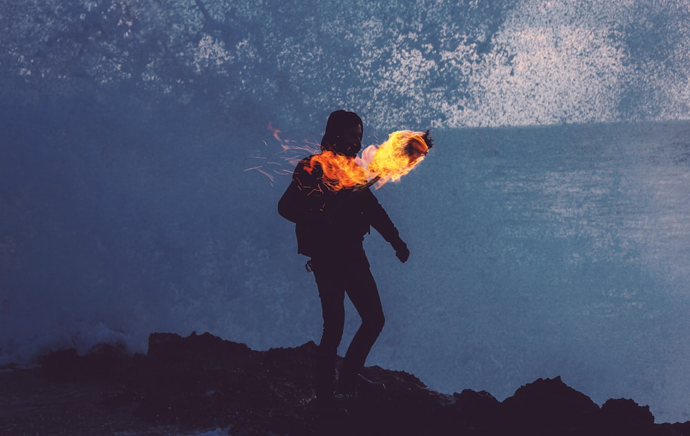 silhouette of man holding fire torch