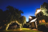 Evening view of a home with holiday lights glowing along the roofline and trees.