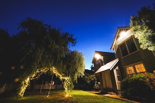Evening view of a home with holiday lights glowing along the roofline and trees.