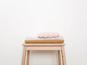 Minimalist wooden step prop staged in a cozy newborn photography setup with soft natural light.